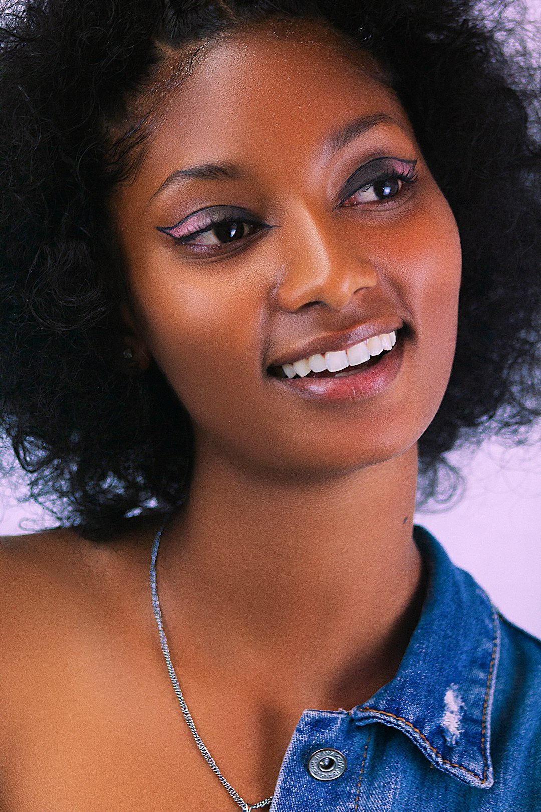 Studio portrait of a woman with curly hair and a bright smile